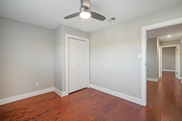 unfurnished bedroom with a closet, dark hardwood / wood-style floors, and ceiling fan