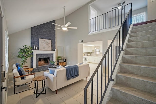 tiled living room with high vaulted ceiling, ceiling fan, and a stone fireplace