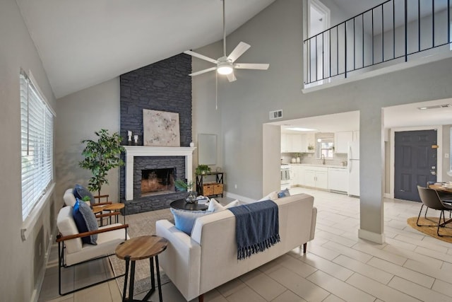 living room featuring ceiling fan, a fireplace, and high vaulted ceiling