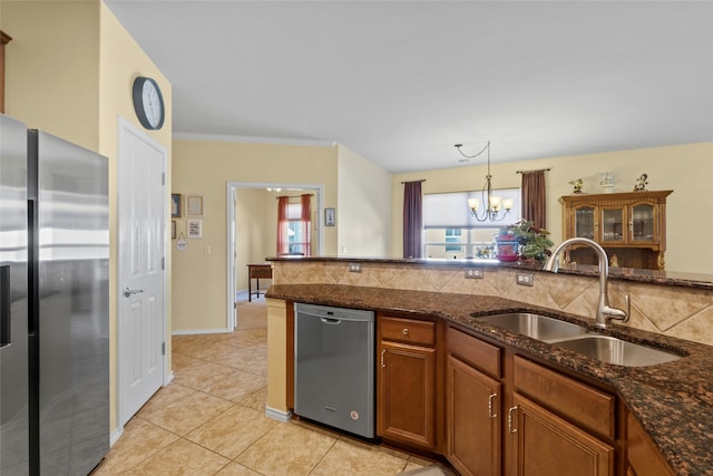 kitchen with appliances with stainless steel finishes, sink, hanging light fixtures, and dark stone countertops