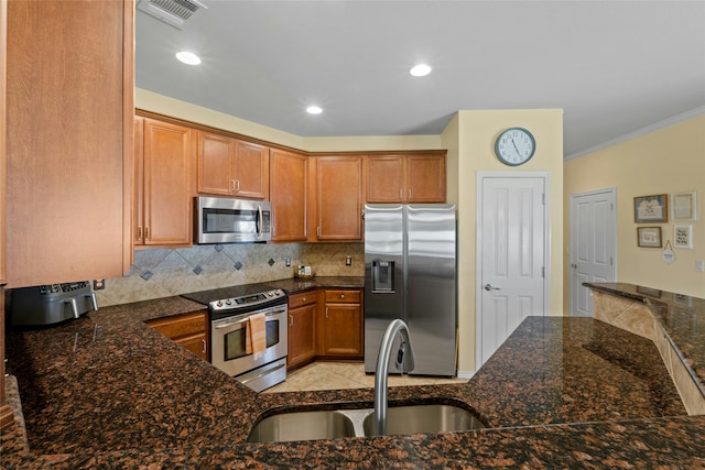 kitchen with sink, dark stone countertops, backsplash, stainless steel appliances, and kitchen peninsula