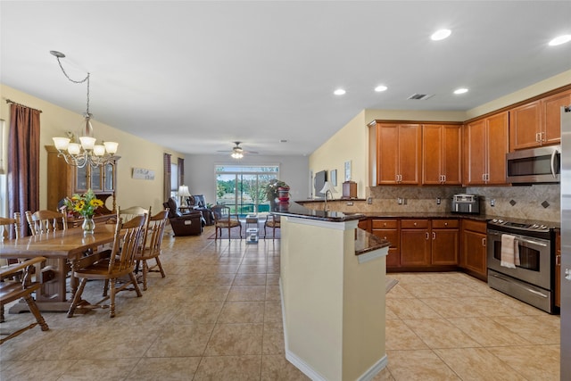 kitchen with appliances with stainless steel finishes, hanging light fixtures, backsplash, light tile patterned flooring, and kitchen peninsula