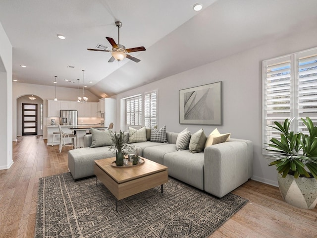 living room featuring hardwood / wood-style floors, ceiling fan with notable chandelier, and lofted ceiling