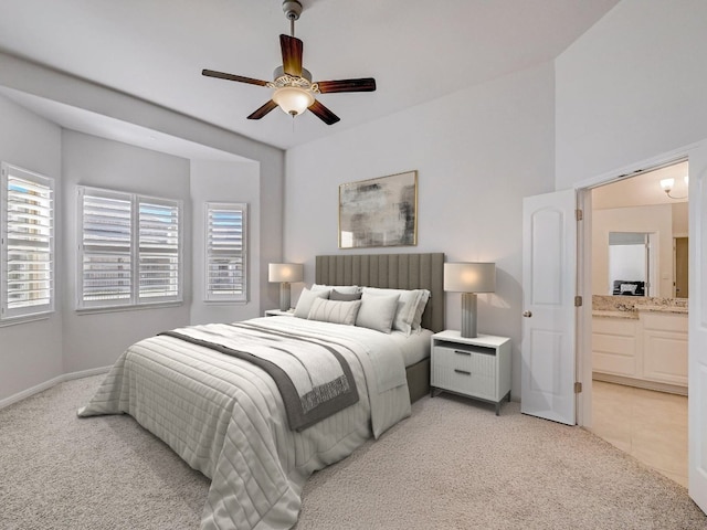 bedroom with connected bathroom, light colored carpet, and ceiling fan