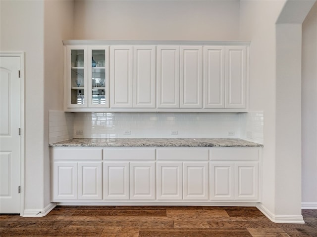 bar featuring tasteful backsplash, white cabinetry, light stone countertops, and dark hardwood / wood-style floors