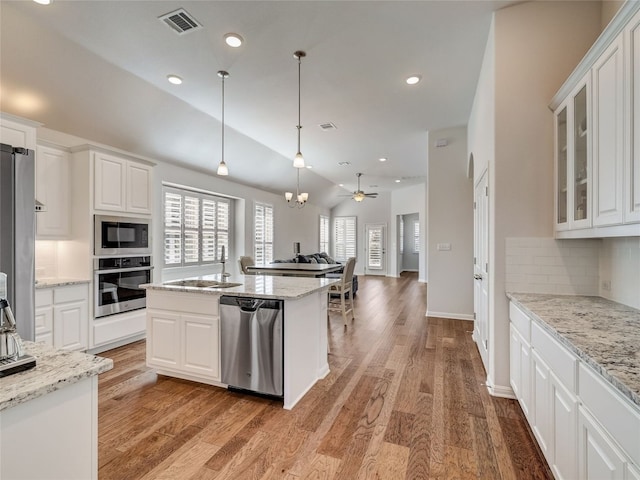 kitchen featuring ceiling fan with notable chandelier, stainless steel appliances, white cabinetry, and an island with sink