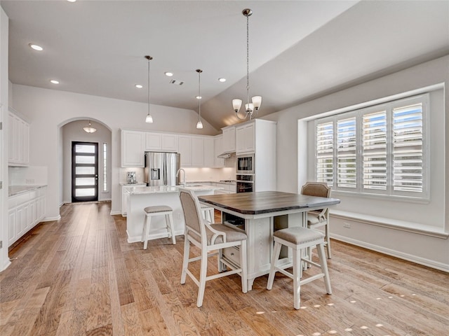 dining area featuring light hardwood / wood-style floors, vaulted ceiling, plenty of natural light, and a notable chandelier