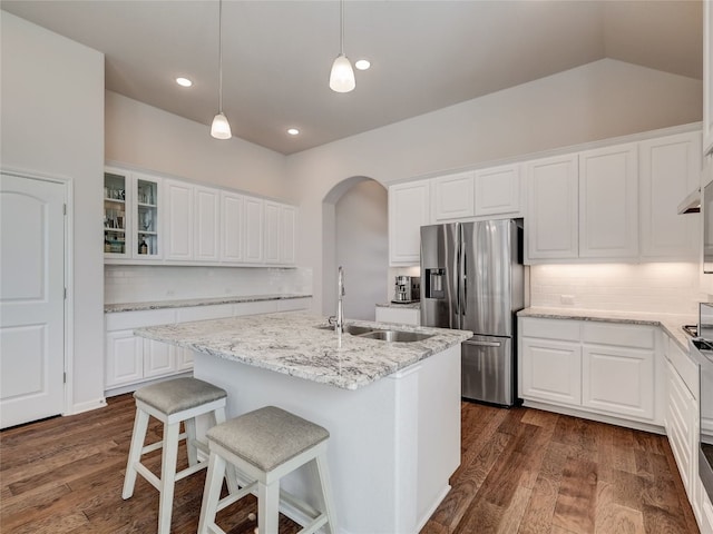 kitchen featuring white cabinets, stainless steel fridge, and an island with sink