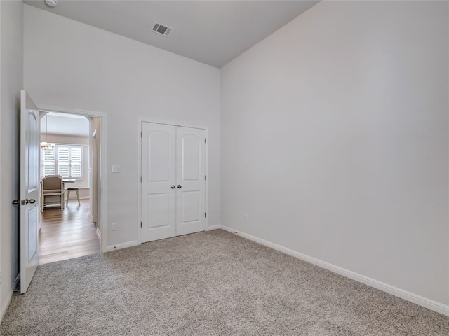 unfurnished bedroom with light colored carpet and a closet