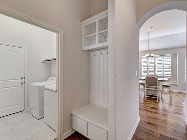 clothes washing area featuring light wood-type flooring, separate washer and dryer, and an inviting chandelier