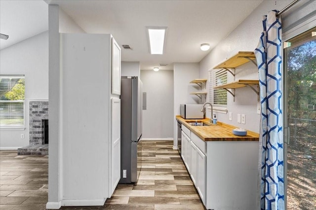 kitchen featuring butcher block counters, white cabinetry, a wealth of natural light, and light wood-type flooring