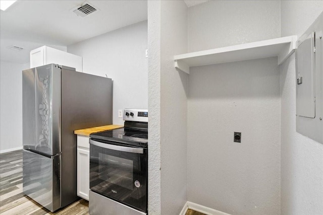 kitchen featuring white cabinets, stainless steel appliances, electric panel, and light hardwood / wood-style flooring