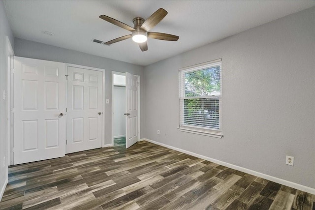 unfurnished bedroom featuring ceiling fan, a closet, and dark wood-type flooring