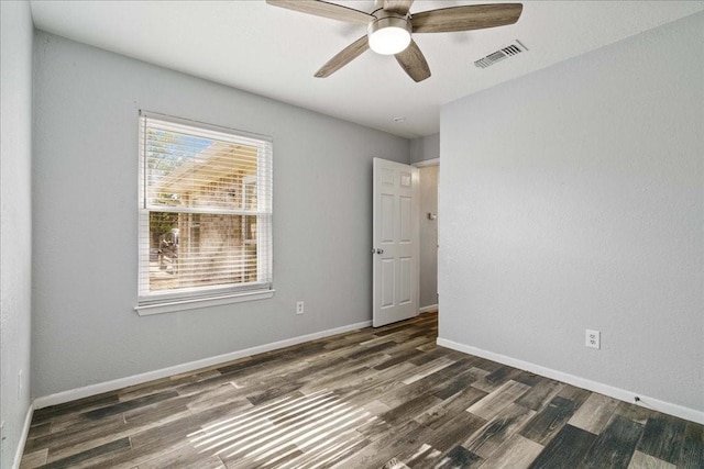 empty room with ceiling fan, a healthy amount of sunlight, and dark hardwood / wood-style flooring