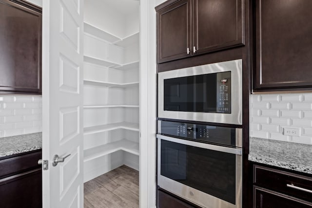 interior space featuring dark brown cabinetry, light stone counters, and appliances with stainless steel finishes