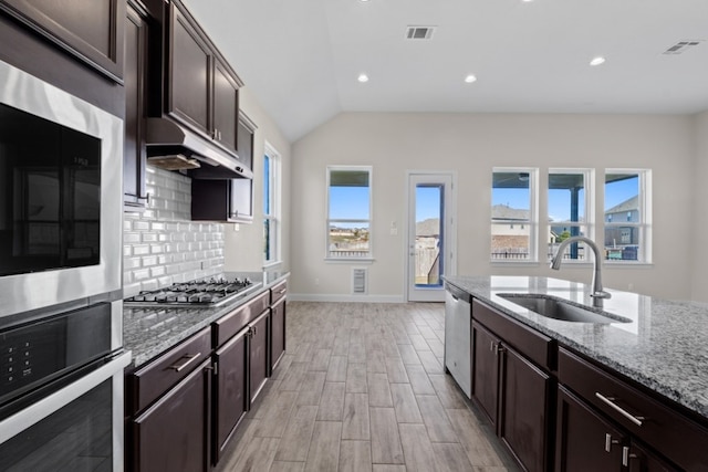 kitchen featuring light stone countertops, sink, stainless steel appliances, tasteful backsplash, and lofted ceiling