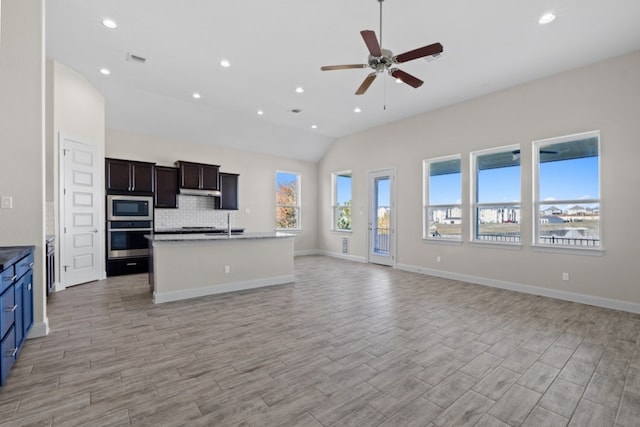 kitchen featuring a kitchen island with sink, light hardwood / wood-style flooring, vaulted ceiling, ceiling fan, and appliances with stainless steel finishes