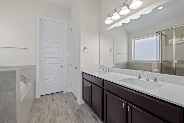 bathroom featuring plus walk in shower, vanity, and hardwood / wood-style flooring