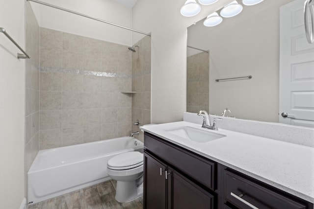 full bathroom with toilet, vanity, wood-type flooring, and tiled shower / bath