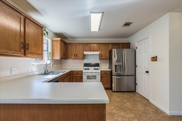 kitchen featuring kitchen peninsula, white gas range, sink, light tile patterned floors, and stainless steel fridge with ice dispenser