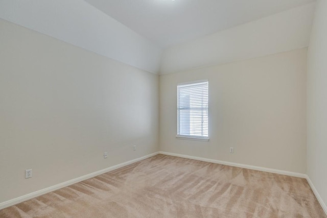 carpeted spare room with vaulted ceiling