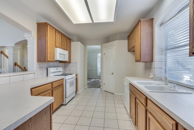 kitchen with sink, decorative columns, white appliances, decorative backsplash, and light tile patterned floors