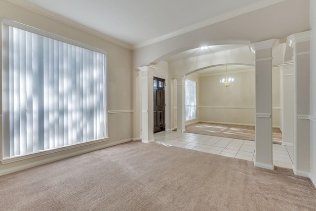 carpeted empty room with decorative columns, an inviting chandelier, and ornamental molding