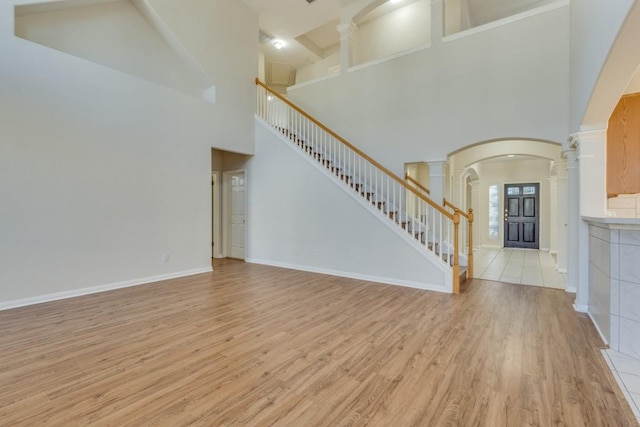 unfurnished living room featuring high vaulted ceiling and light hardwood / wood-style floors