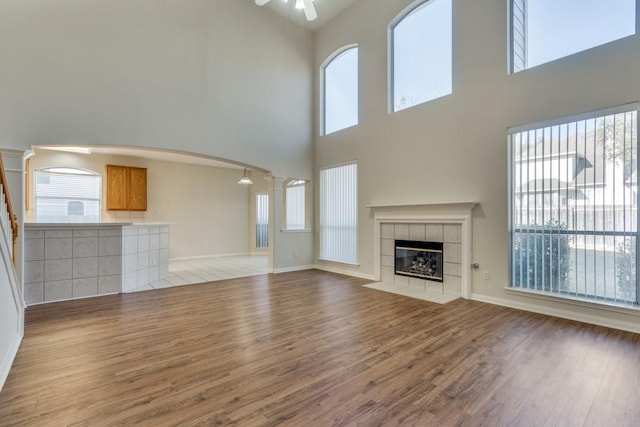 unfurnished living room featuring a tile fireplace, a wealth of natural light, and light hardwood / wood-style flooring