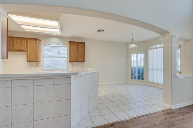 kitchen with pendant lighting, tasteful backsplash, a wealth of natural light, and light hardwood / wood-style flooring