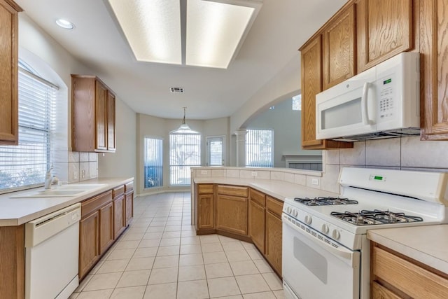 kitchen featuring a wealth of natural light, sink, hanging light fixtures, and white appliances