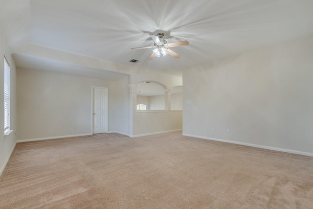 carpeted empty room with decorative columns and ceiling fan