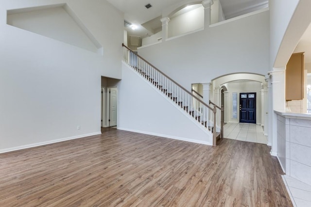 712 Runners Rdg, Pflugerville, TX 78660 - unfurnished living room featuring ornate columns, wood finished floors, a high ceiling, stairs, and arched walkways