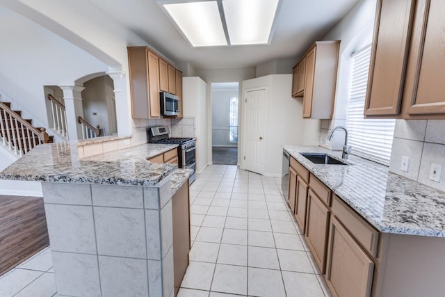 712 Runners Rdg, Pflugerville, TX 78660 - kitchen featuring appliances with stainless steel finishes, ornate columns, a peninsula, light tile patterned floors, and light stone counters