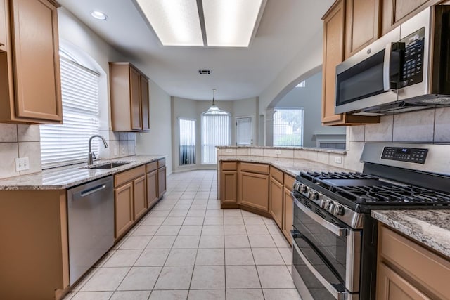 712 Runners Rdg, Pflugerville, TX 78660 - kitchen with appliances with stainless steel finishes, backsplash, light stone counters, light tile patterned floors, and arched walkways