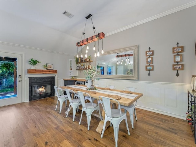 dining area featuring crown molding, wood-type flooring, and vaulted ceiling