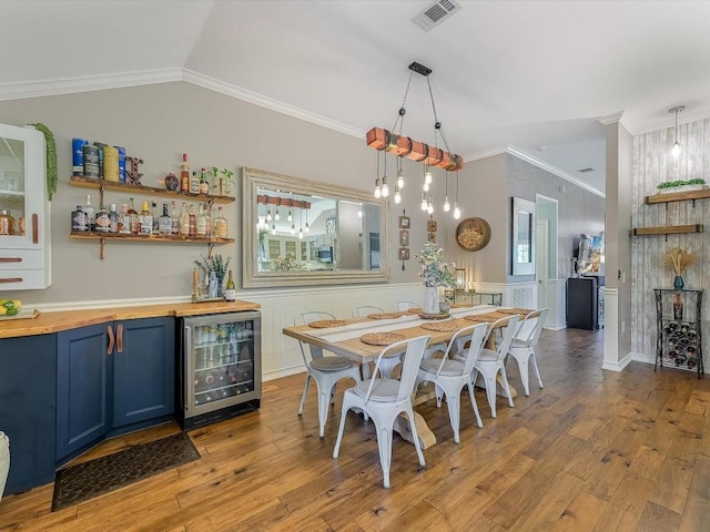 dining area with wine cooler, vaulted ceiling, bar, and light hardwood / wood-style flooring