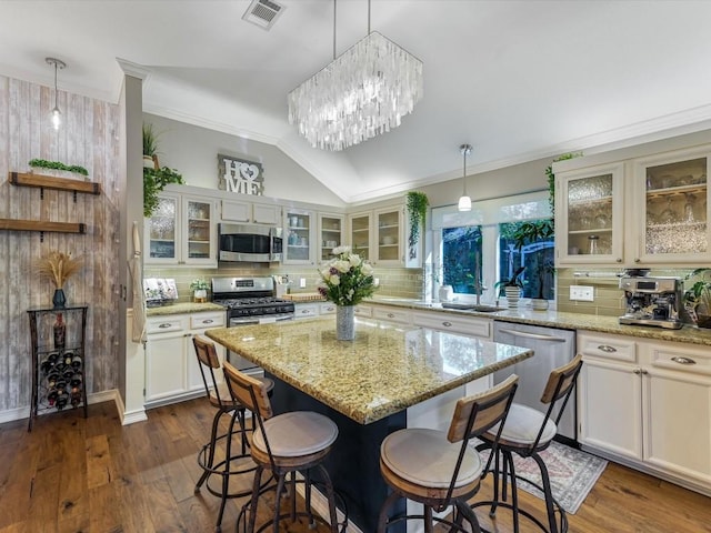 kitchen featuring tasteful backsplash, dark wood-type flooring, a kitchen island, and stainless steel appliances