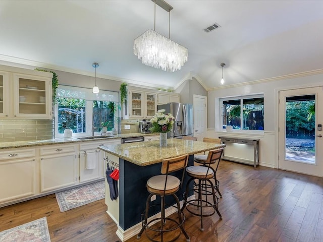 kitchen featuring dark hardwood / wood-style flooring, a center island, stainless steel appliances, and hanging light fixtures