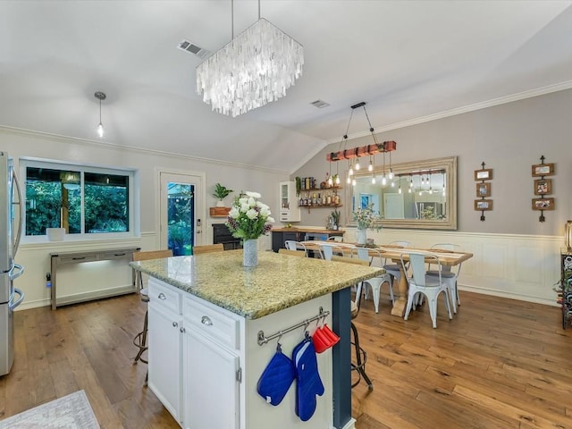 kitchen featuring white cabinetry, light hardwood / wood-style flooring, hanging light fixtures, and lofted ceiling