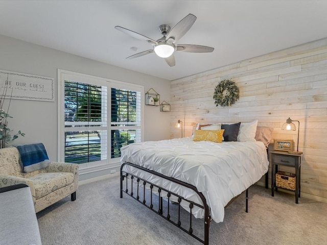 bedroom featuring ceiling fan, light colored carpet, and wooden walls