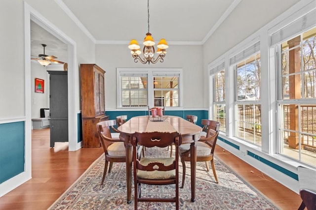 dining area with a notable chandelier, crown molding, and wood finished floors