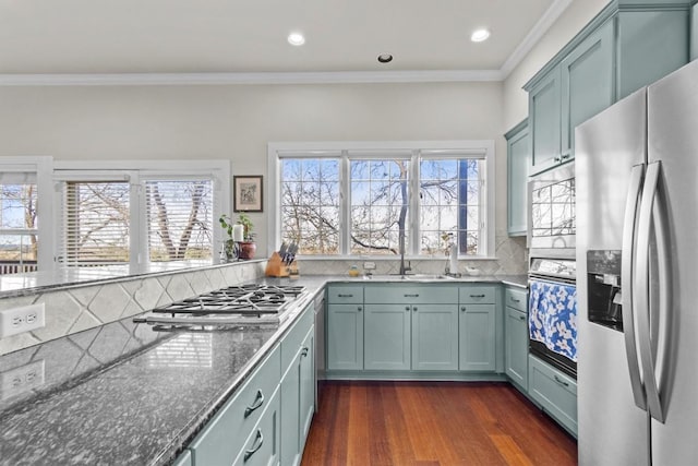 kitchen with appliances with stainless steel finishes, tasteful backsplash, ornamental molding, dark wood-type flooring, and sink