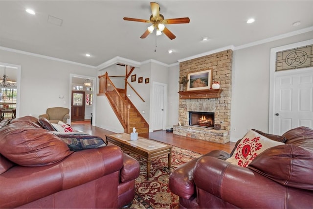 living room with ornamental molding, wood finished floors, and a stone fireplace