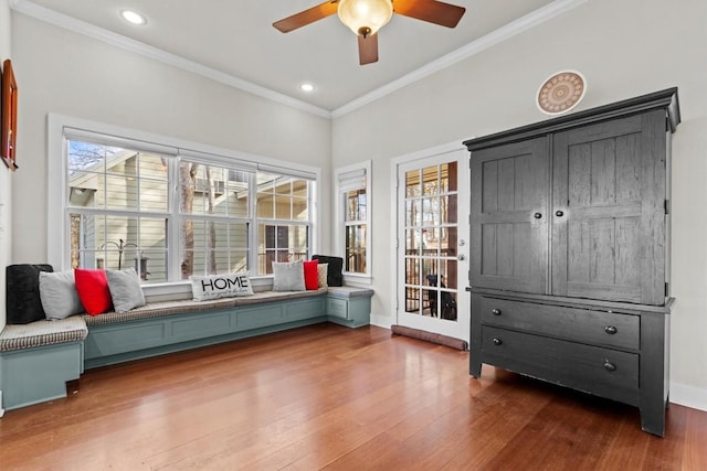 living area with dark wood-style floors, ornamental molding, baseboards, and a ceiling fan