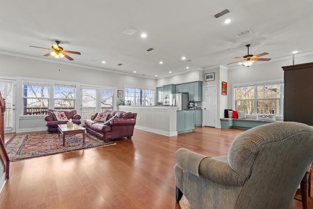 living room featuring light wood-type flooring, ceiling fan, and crown molding