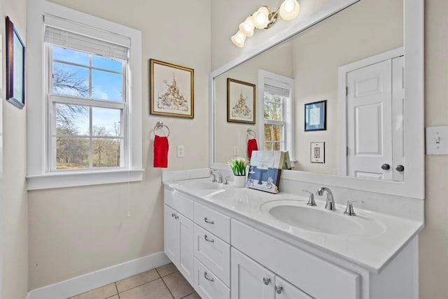 full bathroom with double vanity, tile patterned flooring, a sink, and baseboards