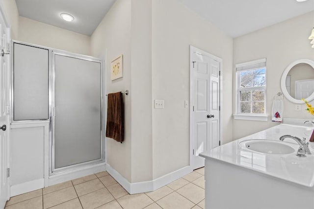 bathroom featuring tile patterned flooring, baseboards, a sink, and a shower stall