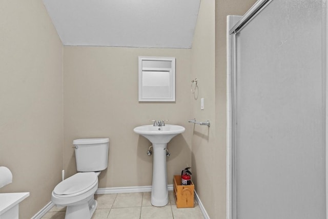 bathroom featuring toilet, a shower with shower door, a sink, tile patterned flooring, and baseboards