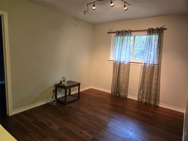 spare room featuring track lighting and dark hardwood / wood-style floors